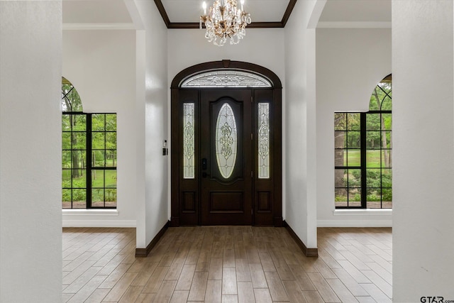 entryway featuring wood-type flooring, a chandelier, and crown molding