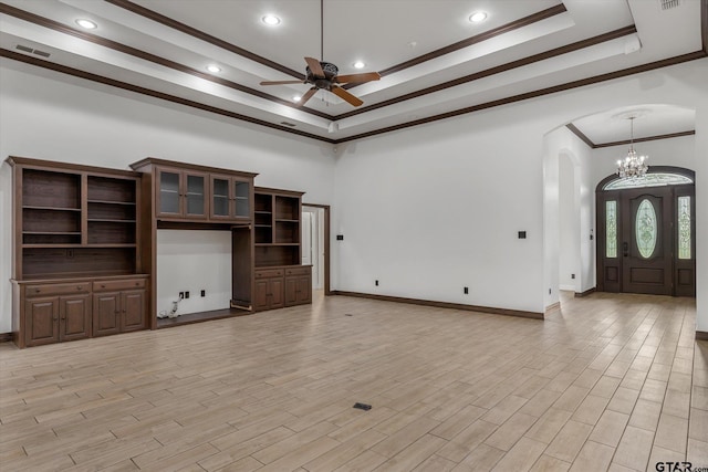 unfurnished living room with light hardwood / wood-style floors, ceiling fan with notable chandelier, crown molding, and a tray ceiling