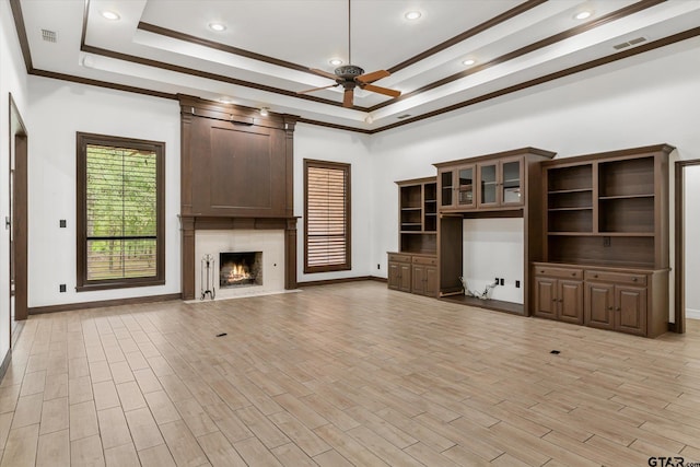 unfurnished living room featuring ornamental molding, light hardwood / wood-style floors, ceiling fan, and a tray ceiling