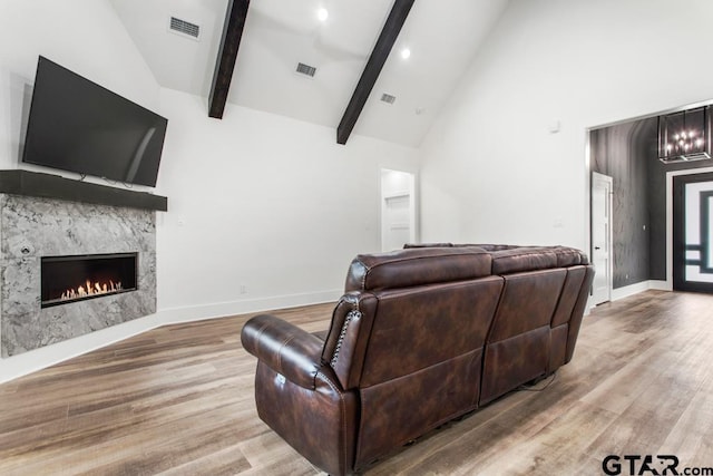 living room with a fireplace, high vaulted ceiling, light hardwood / wood-style floors, and beamed ceiling