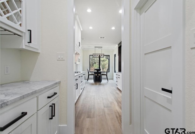 corridor featuring light wood-type flooring and crown molding