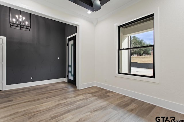 empty room with wood-type flooring and a chandelier