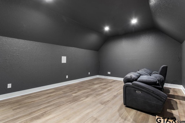 additional living space with light hardwood / wood-style flooring and lofted ceiling