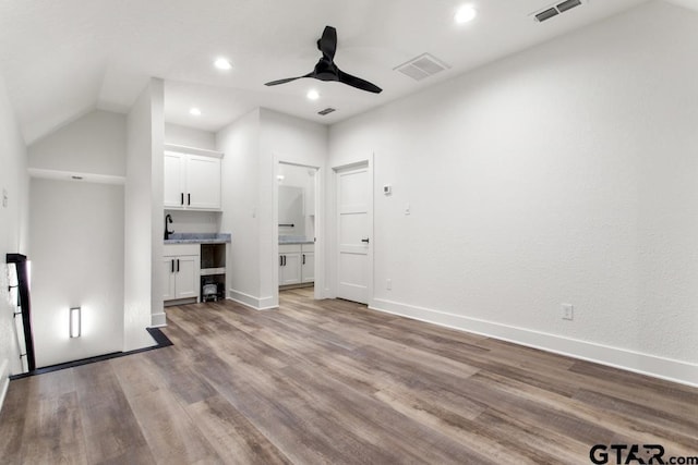 unfurnished living room with ceiling fan, light wood-type flooring, sink, and vaulted ceiling