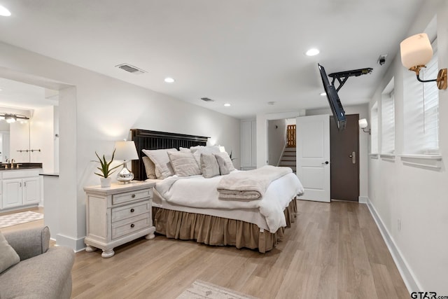 bedroom featuring sink, connected bathroom, and light hardwood / wood-style flooring