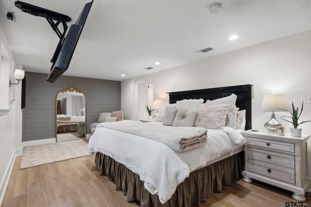 bedroom with wood walls and light hardwood / wood-style floors