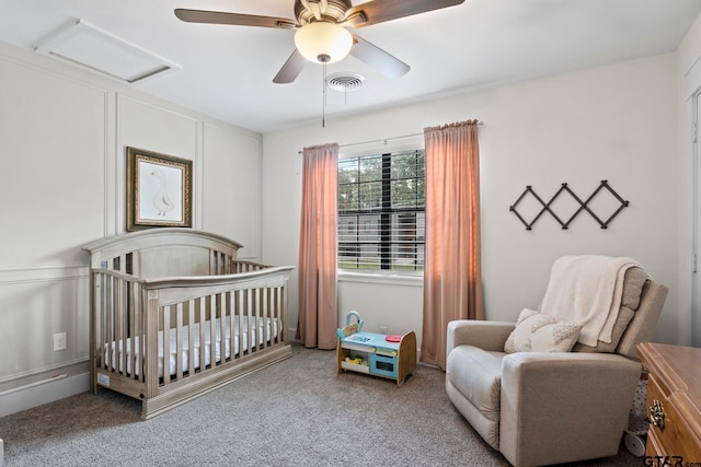 carpeted bedroom featuring a crib and ceiling fan