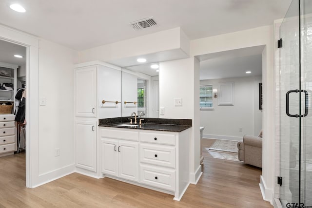 bathroom with wood-type flooring, vanity, and a shower with shower door