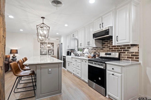 kitchen featuring stainless steel appliances, white cabinetry, a kitchen island, and light stone counters