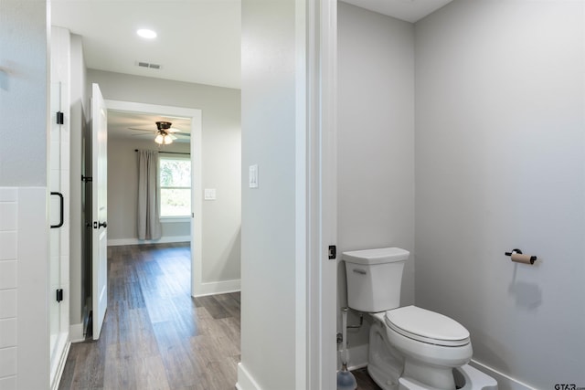 bathroom with toilet, hardwood / wood-style flooring, ceiling fan, and a shower with door