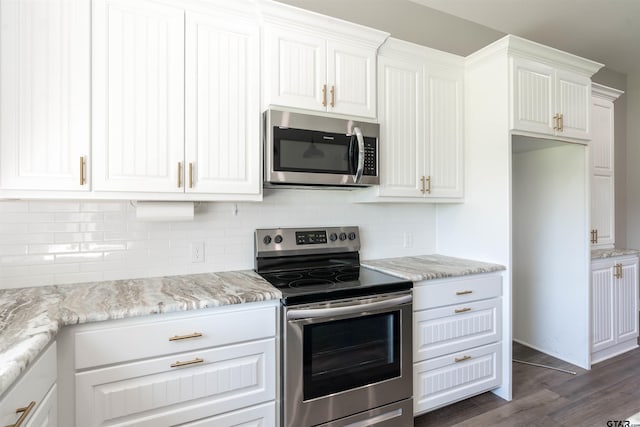 kitchen with light stone counters, stainless steel appliances, backsplash, white cabinetry, and dark hardwood / wood-style flooring