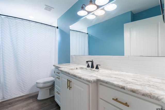 bathroom featuring toilet, wood-type flooring, vanity, and backsplash