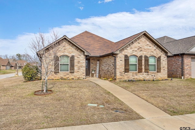 french provincial home featuring brick siding and a front yard