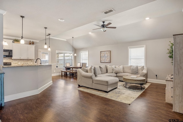 living room with a wealth of natural light, visible vents, dark wood-style floors, lofted ceiling, and ceiling fan