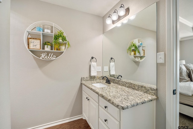 bathroom featuring vanity, ensuite bath, wood finished floors, and baseboards