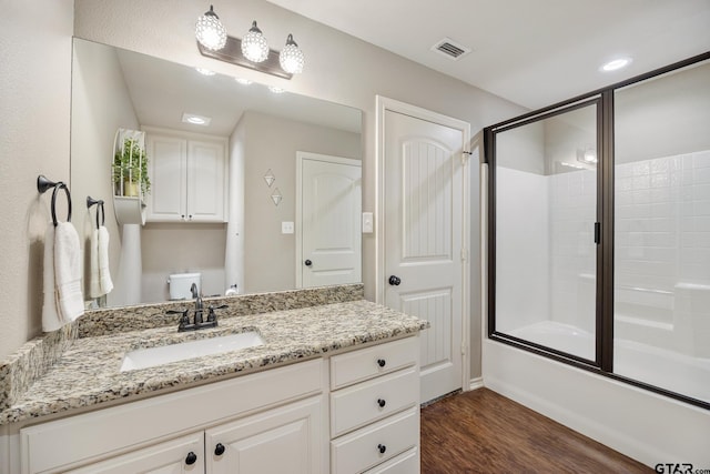 full bathroom featuring vanity, wood finished floors, visible vents, shower / bath combination with glass door, and recessed lighting