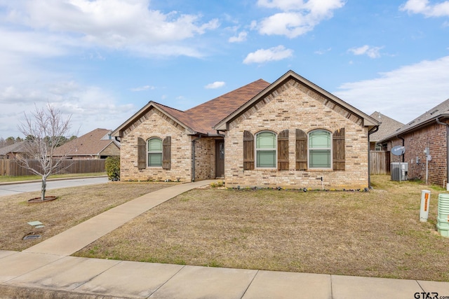 view of front of property featuring brick siding, central AC, a front lawn, and fence