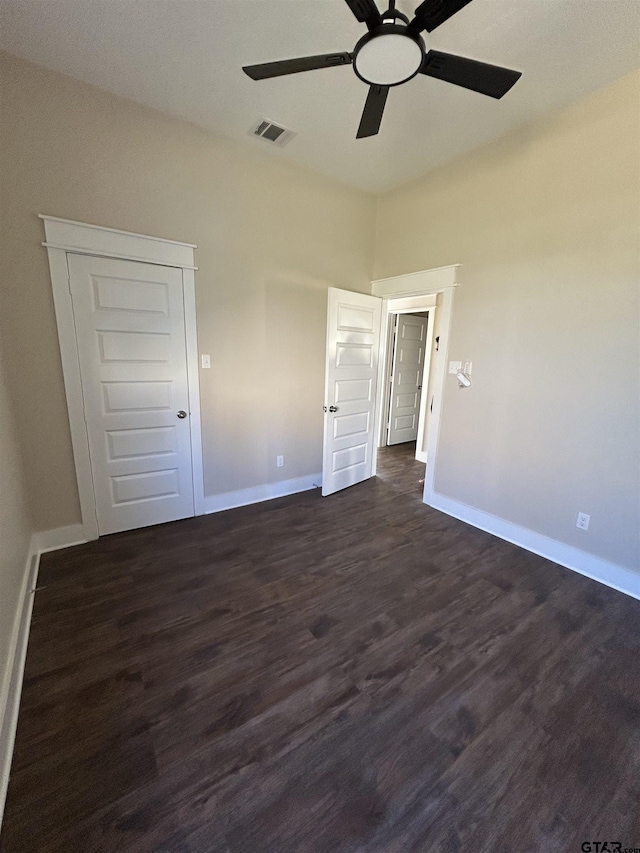 unfurnished bedroom with ceiling fan, dark wood-type flooring, and a closet