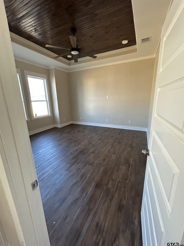 spare room featuring dark hardwood / wood-style flooring, wood ceiling, a tray ceiling, ceiling fan, and crown molding