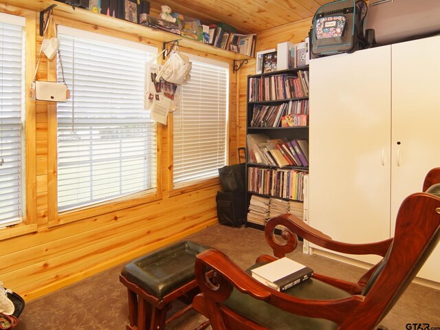 sitting room featuring wooden ceiling, carpet flooring, and wood walls