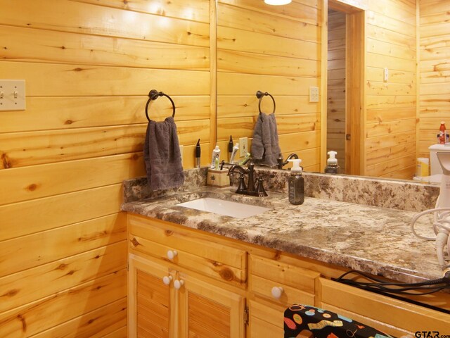 bathroom with wooden walls, toilet, and vanity