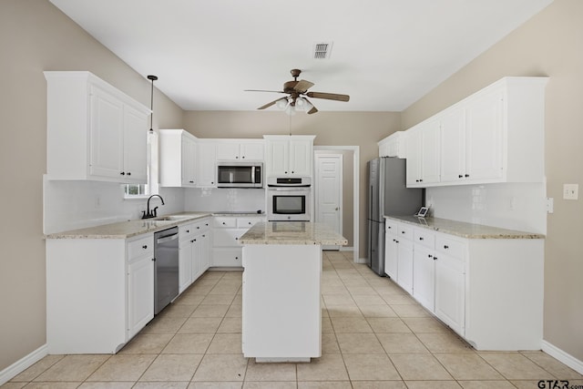 kitchen with light stone counters, stainless steel appliances, sink, a center island, and white cabinetry