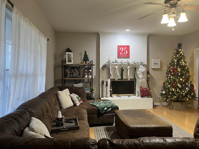 living room with ceiling fan, hardwood / wood-style floors, and a brick fireplace