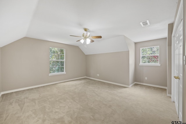 additional living space featuring light colored carpet, vaulted ceiling, and a healthy amount of sunlight