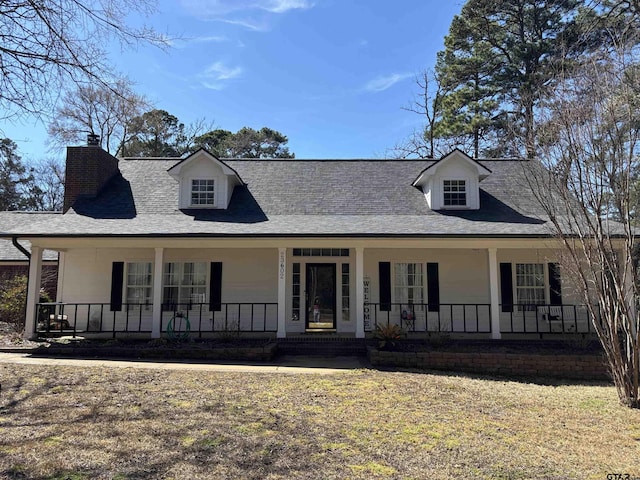 view of front facade with a porch, a shingled roof, and a chimney