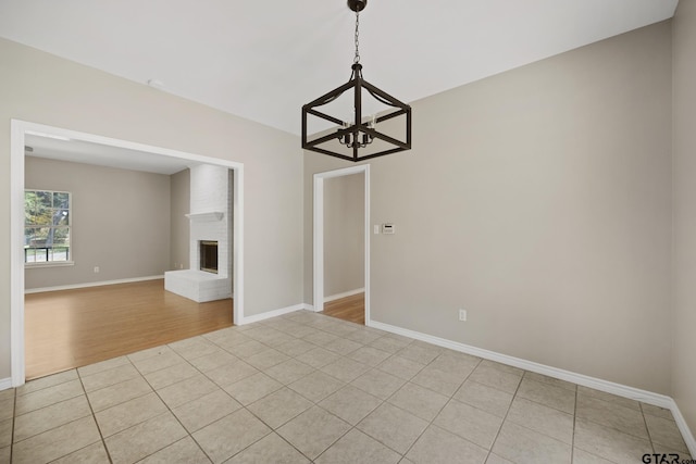 interior space featuring a notable chandelier, light wood-type flooring, and a brick fireplace