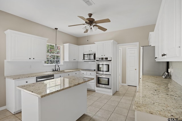 kitchen featuring a center island, ceiling fan, light stone countertops, appliances with stainless steel finishes, and white cabinetry