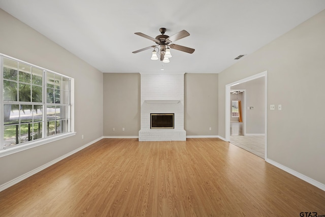 unfurnished living room featuring ceiling fan, a fireplace, and light hardwood / wood-style flooring