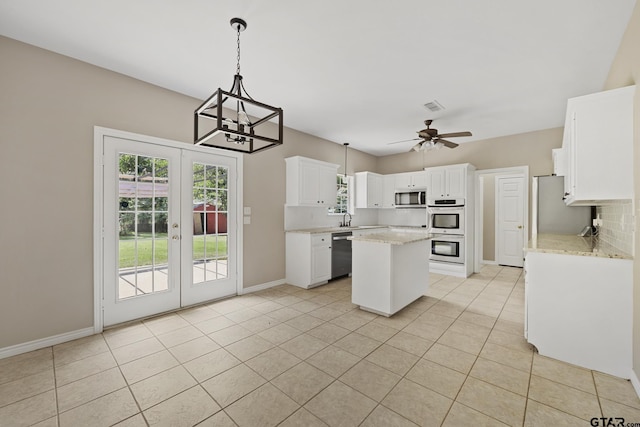 kitchen with white cabinetry, french doors, stainless steel appliances, a kitchen island, and ceiling fan with notable chandelier