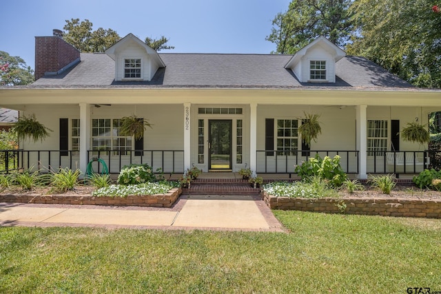 view of front of property featuring covered porch, roof with shingles, and a front yard