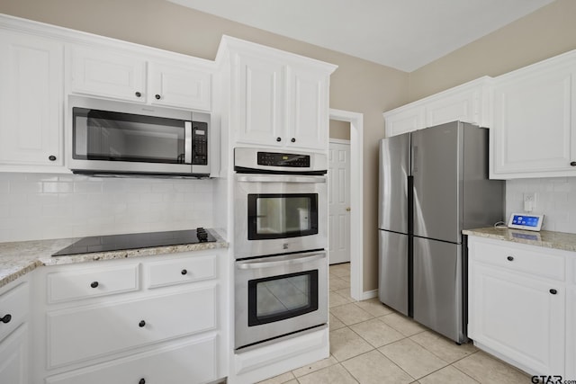 kitchen with light stone countertops, tasteful backsplash, stainless steel appliances, white cabinets, and light tile patterned flooring