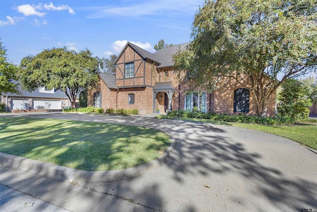 tudor house featuring a garage and a front lawn