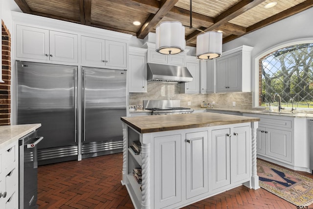 kitchen featuring built in fridge, extractor fan, wood counters, sink, and stove