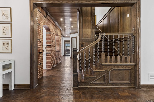 stairs with hardwood / wood-style flooring and brick wall