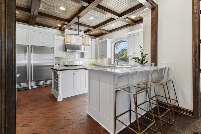 kitchen featuring a kitchen bar, tasteful backsplash, decorative light fixtures, stainless steel appliances, and white cabinets