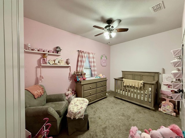 bedroom featuring a nursery area, ceiling fan, and carpet flooring