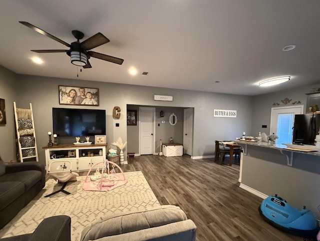 living room with ceiling fan and dark hardwood / wood-style flooring