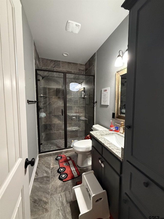 bathroom with a shower with door, vanity, and toilet