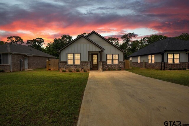 509 Zimmerman Dr, Jacksonville, TX 75766 - bungalow-style house with fence, brick siding, board and batten siding, concrete driveway, and a lawn