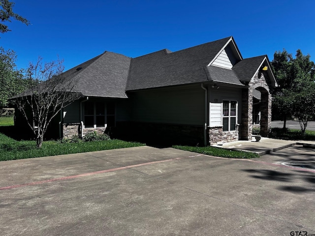 view of home's exterior featuring stone siding and a shingled roof