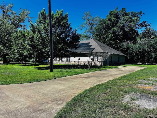 view of property exterior with a yard and solar panels