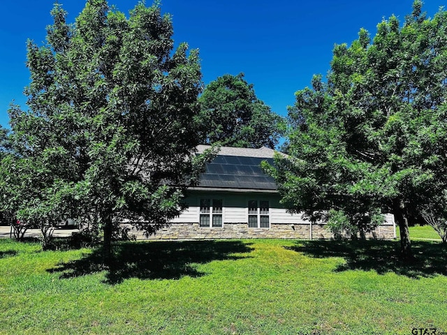 exterior space with roof mounted solar panels and a lawn