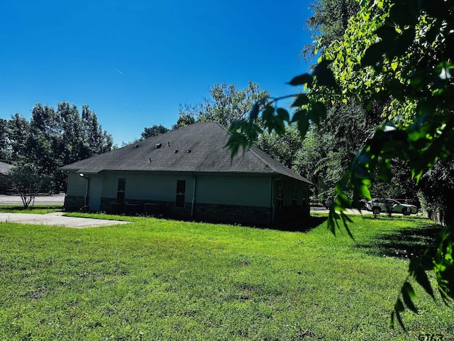 view of side of property featuring a yard and a shingled roof