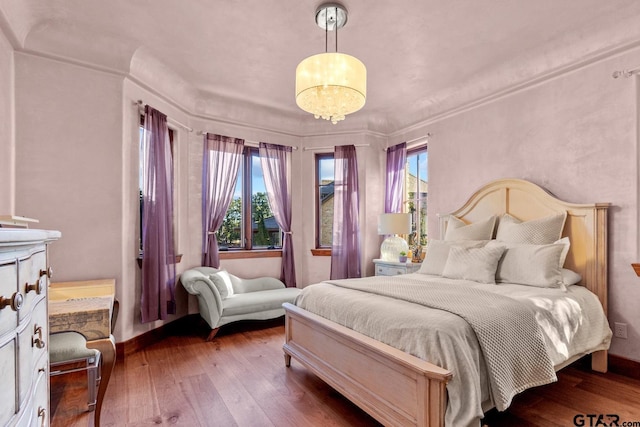 bedroom with multiple windows, hardwood / wood-style floors, and an inviting chandelier