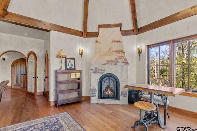 living room featuring wood-type flooring, a high ceiling, a large fireplace, and a healthy amount of sunlight