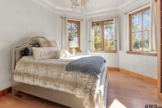 bedroom featuring crown molding, a chandelier, and light wood-type flooring